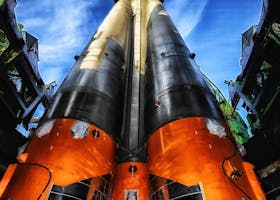 A vibrant low angle view of a rocket on a launch pad against a clear blue sky.