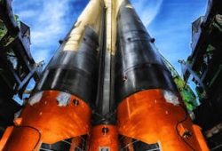 A vibrant low angle view of a rocket on a launch pad against a clear blue sky.