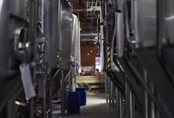 Inside view of a modern brewery with large stainless steel tanks and machinery for beer production.